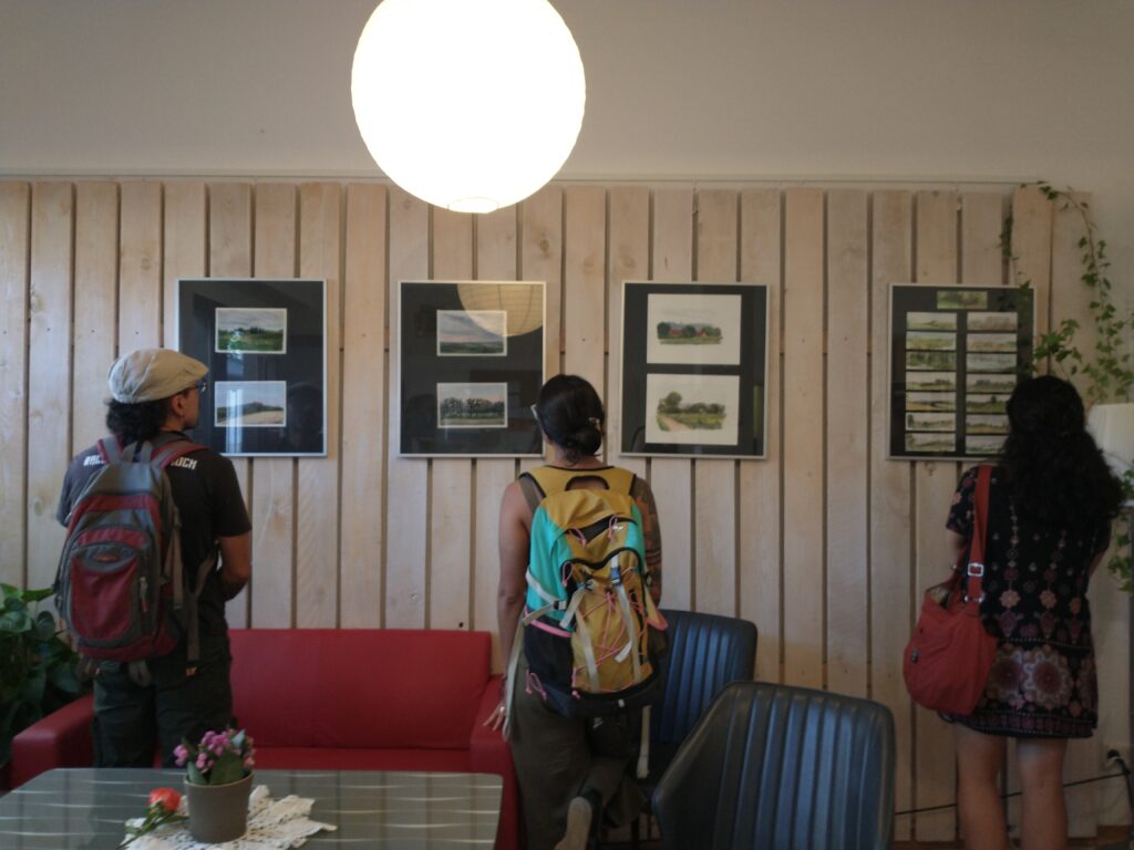 Three people looking at paintings hanging on a wall